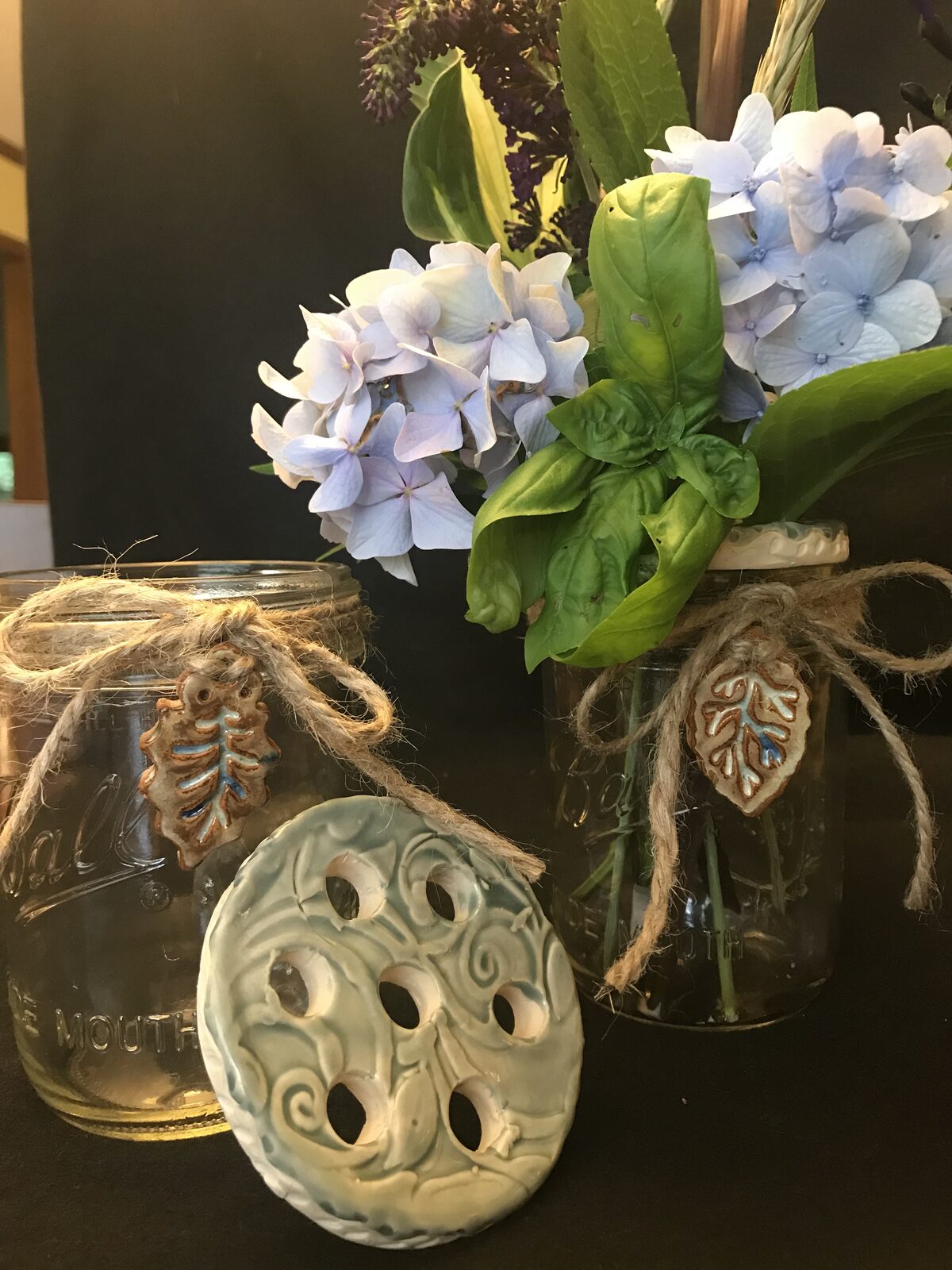 Ceramic flower frog and leaf-shaped charms with mason jars holding hydrangeas