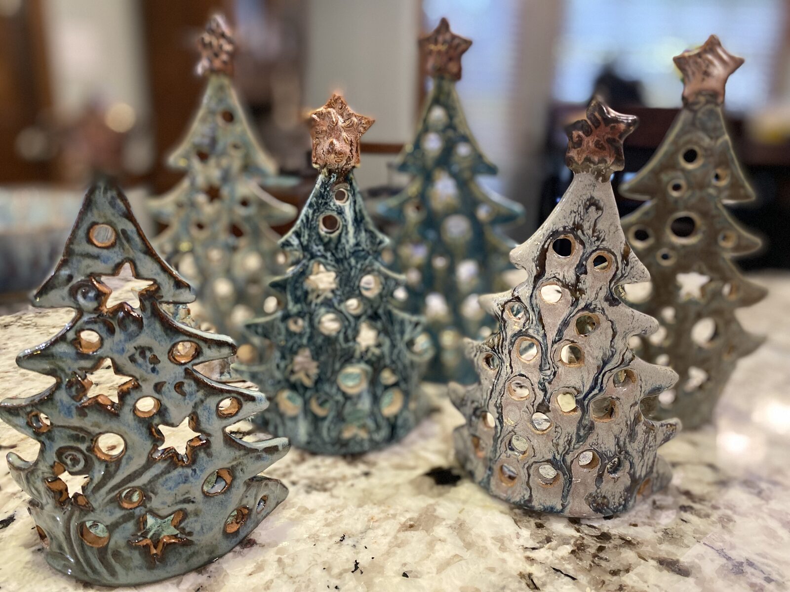 Group of ceramic Christmas trees with cutout patterns and copper-glazed star toppers, designed as candle lanterns