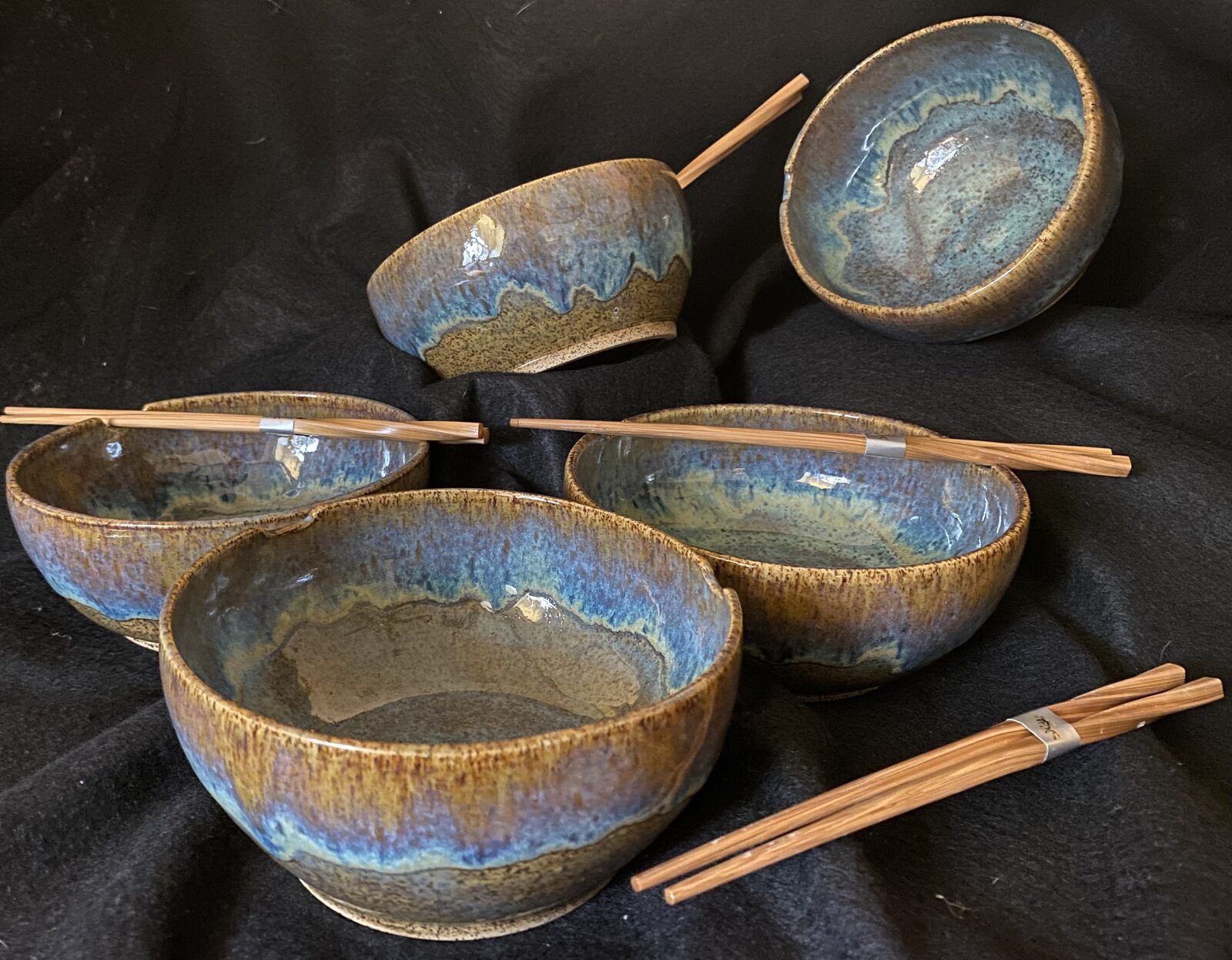 Set of noodle bowls with chopstick rest notches in the rim, earthy blue and tan glaze, presented with chopsticks